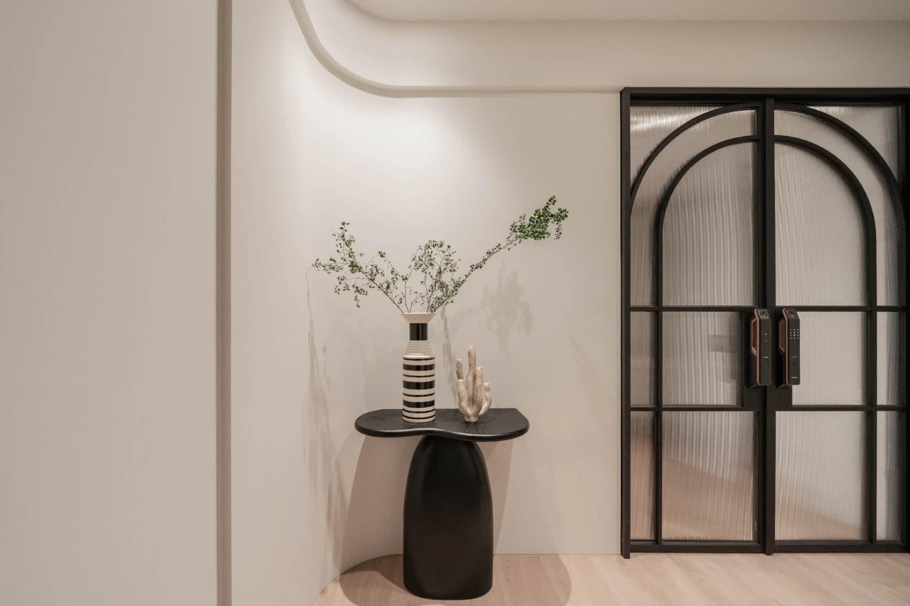 赫里翁城堡別墅2F主臥入口端景。安頡建築運用自由曲線牆面、黑色極簡藝術端景台與條紋玻璃鐵件拱門，彰顯返璞歸真的人生儀式感。